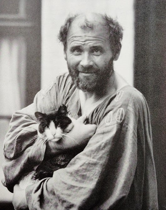 Gustav Klimt en blouse d’atelier tenant un chat dans ses bras
